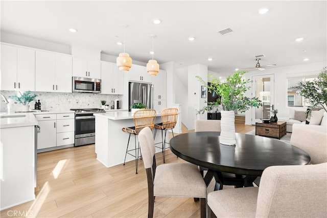 kitchen featuring ceiling fan, white cabinetry, appliances with stainless steel finishes, and hanging light fixtures