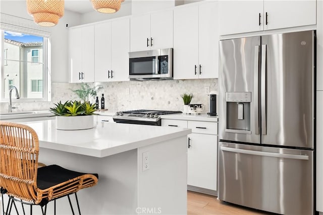 kitchen featuring sink, white cabinets, appliances with stainless steel finishes, and a breakfast bar