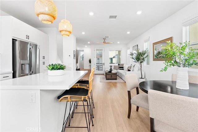 kitchen with decorative light fixtures, white cabinetry, stainless steel fridge, light wood-type flooring, and ceiling fan