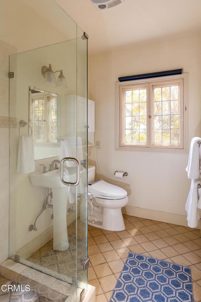 bathroom featuring toilet, tile patterned flooring, and a shower with door