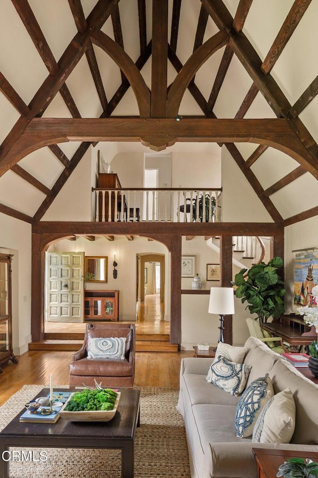 living room with high vaulted ceiling, beam ceiling, and hardwood / wood-style flooring