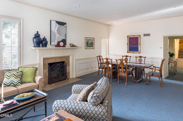 carpeted living room featuring a tile fireplace and crown molding