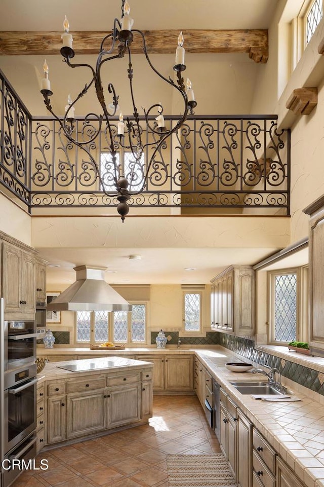 kitchen with stainless steel double oven, black electric stovetop, sink, island range hood, and tile countertops