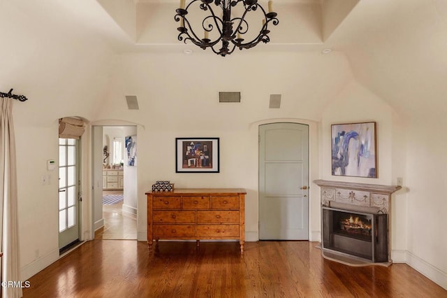 interior space with an inviting chandelier, a towering ceiling, dark hardwood / wood-style floors, and a tray ceiling