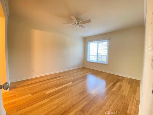 empty room with a ceiling fan, light wood-style flooring, and baseboards