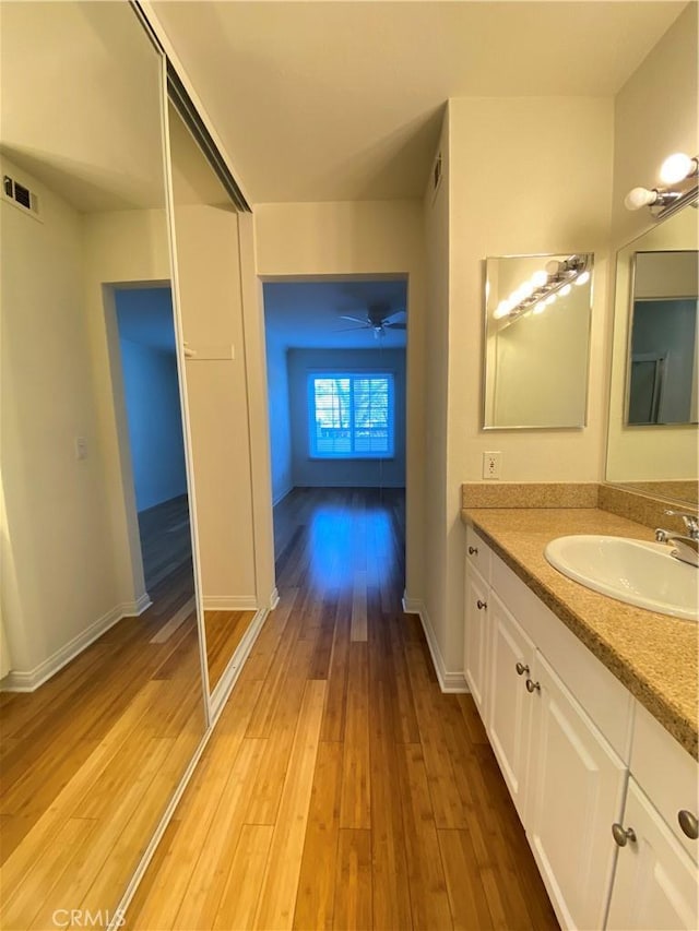 bathroom featuring wood finished floors, vanity, a ceiling fan, visible vents, and baseboards