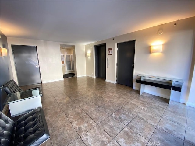 unfurnished living room with elevator, baseboards, and tile patterned floors