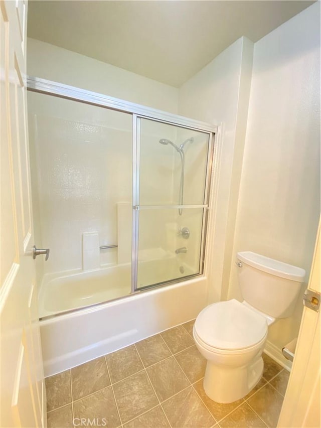 bathroom featuring toilet, shower / bath combination with glass door, and tile patterned flooring