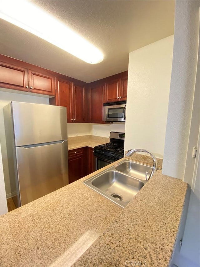 kitchen featuring stainless steel appliances, light countertops, a sink, and a textured ceiling