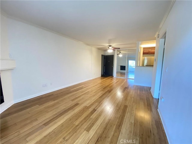 unfurnished living room with ceiling fan, wood-type flooring, baseboards, and crown molding