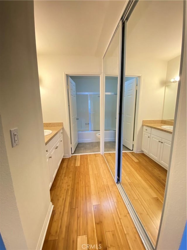 bathroom featuring hardwood / wood-style flooring, vanity, and combined bath / shower with glass door