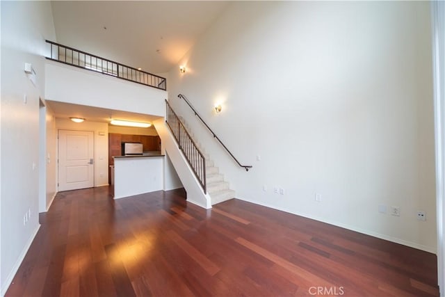 unfurnished living room with a high ceiling and dark hardwood / wood-style flooring