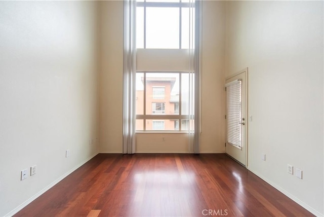 unfurnished room featuring a high ceiling and dark hardwood / wood-style flooring