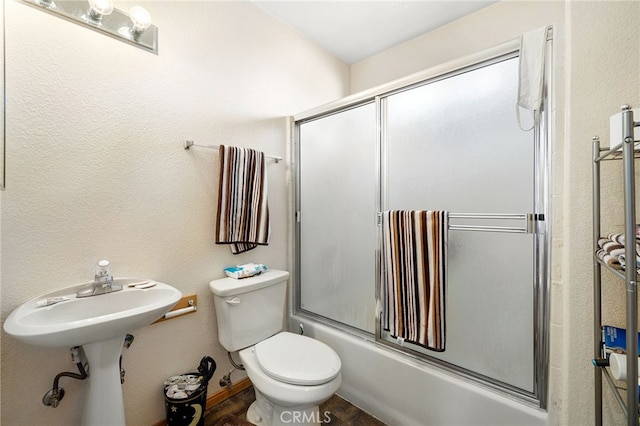 full bathroom with toilet, bath / shower combo with glass door, and sink