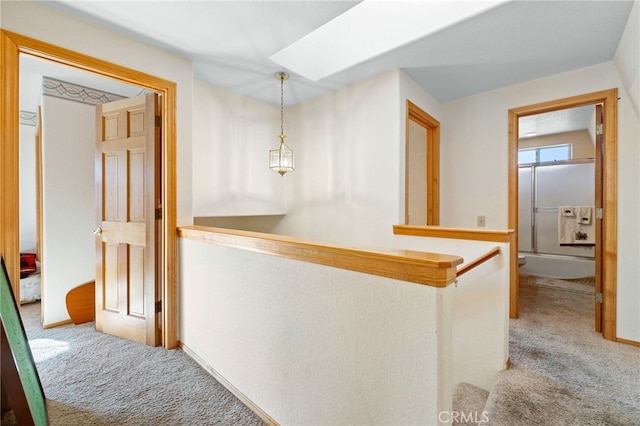 hall with light colored carpet and a skylight