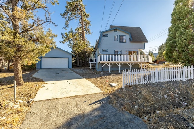 view of front of home with a garage, a wooden deck, and an outbuilding