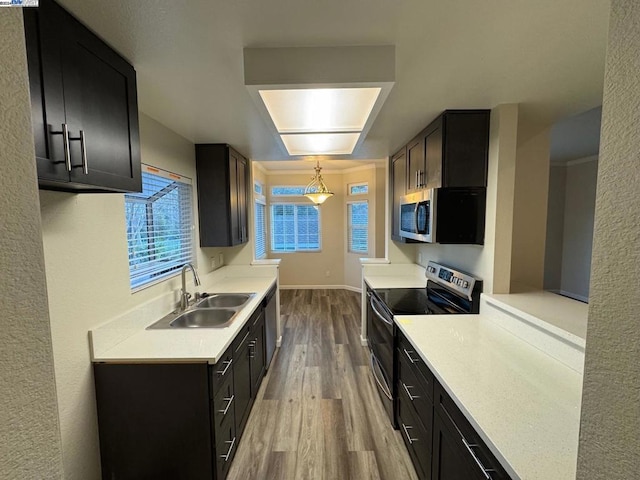 kitchen featuring light wood-type flooring, sink, stainless steel appliances, and pendant lighting