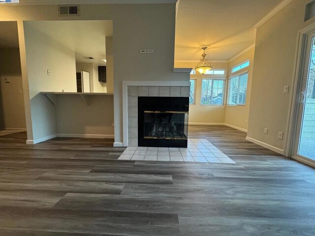 unfurnished living room featuring crown molding, hardwood / wood-style flooring, and a tile fireplace