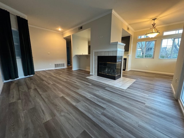 unfurnished living room with a tile fireplace, ornamental molding, and hardwood / wood-style floors