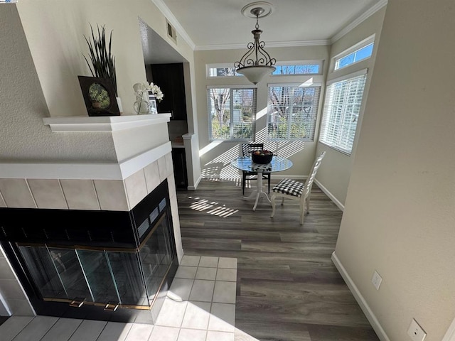 interior space featuring hardwood / wood-style flooring, ornamental molding, and a tiled fireplace