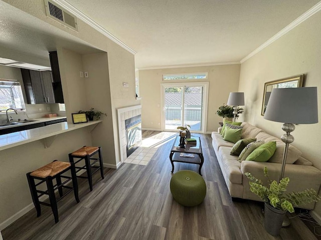 living room featuring crown molding, dark hardwood / wood-style flooring, sink, and a textured ceiling