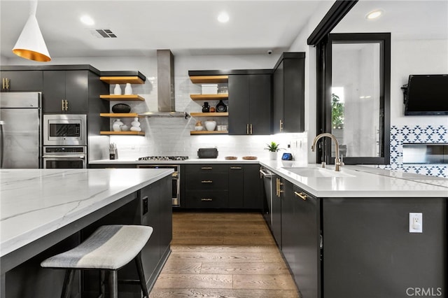 kitchen with a kitchen bar, sink, appliances with stainless steel finishes, dark hardwood / wood-style flooring, and wall chimney range hood