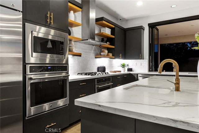 kitchen featuring island exhaust hood, appliances with stainless steel finishes, light stone counters, and decorative backsplash