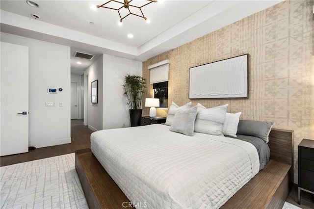 bedroom with an inviting chandelier, a tray ceiling, and dark hardwood / wood-style flooring