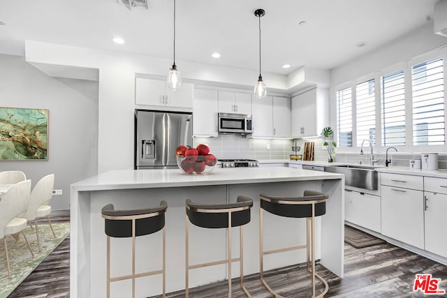 kitchen with backsplash, a center island, sink, appliances with stainless steel finishes, and white cabinets