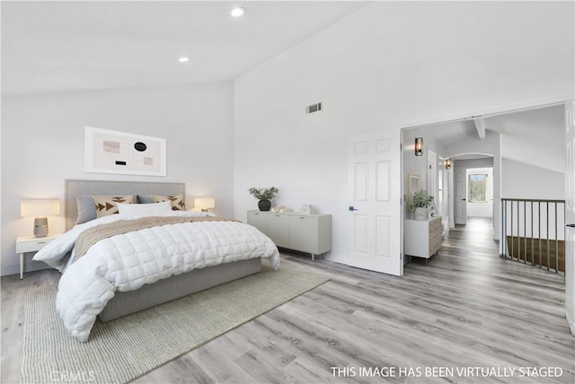 bedroom featuring lofted ceiling with beams and light hardwood / wood-style floors