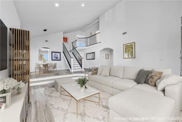 living room featuring light wood-type flooring and high vaulted ceiling