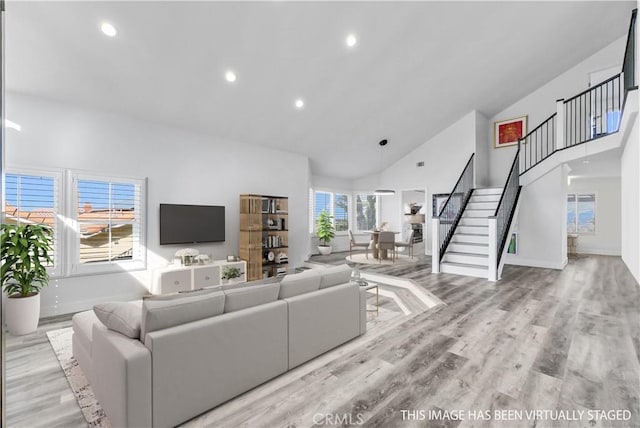 living room featuring a healthy amount of sunlight, light hardwood / wood-style flooring, and high vaulted ceiling