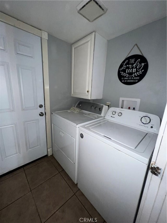 laundry room featuring dark tile patterned floors, washer and clothes dryer, and cabinets