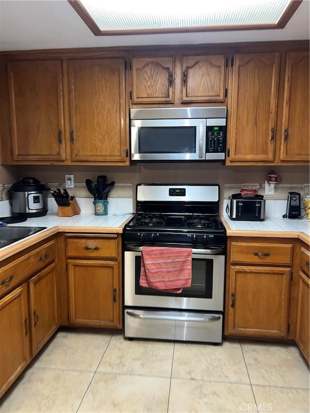 kitchen featuring light tile patterned floors, stainless steel appliances, and tile counters