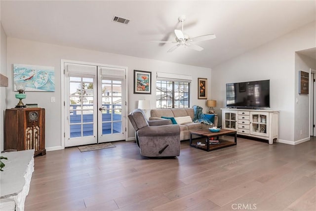 living room with ceiling fan, hardwood / wood-style floors, french doors, and vaulted ceiling