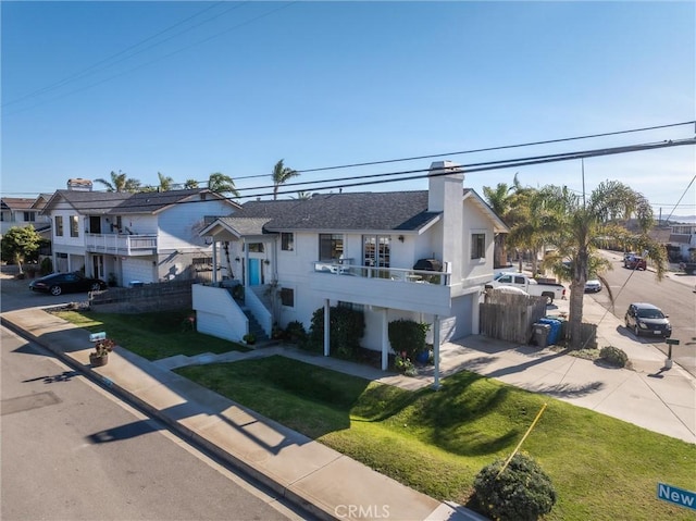 view of front of house featuring a balcony and a front yard