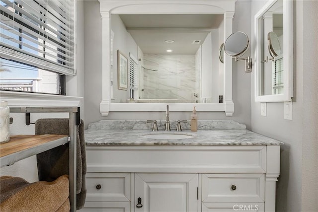 bathroom featuring tiled shower and vanity