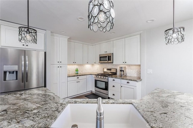 kitchen with white cabinets, pendant lighting, and stainless steel appliances