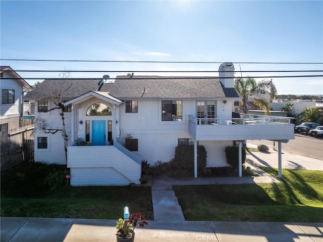 view of front of home with a balcony and a front lawn