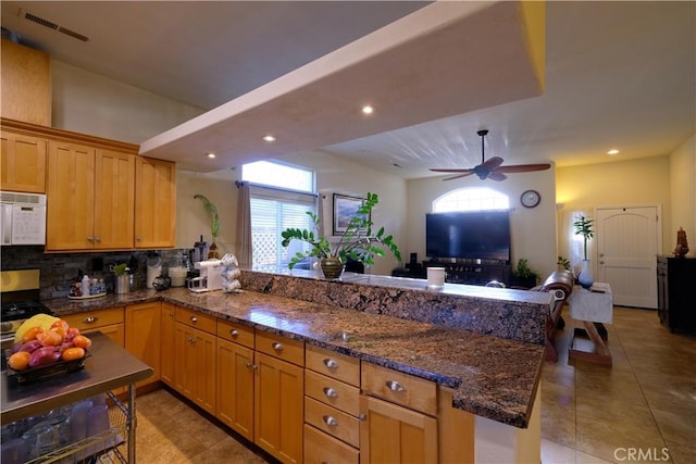 kitchen with ceiling fan, backsplash, stainless steel range, light tile patterned flooring, and dark stone counters