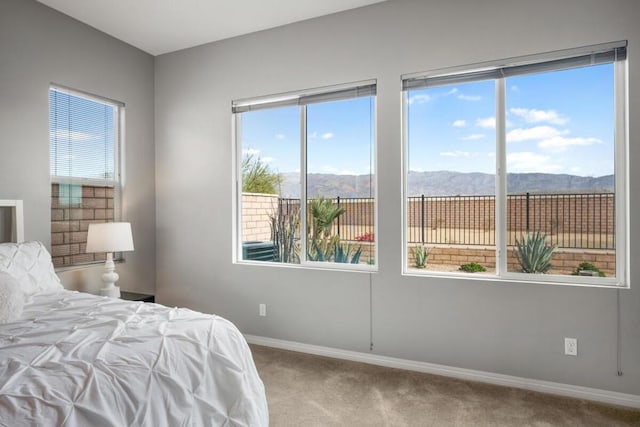 carpeted bedroom featuring a mountain view and multiple windows