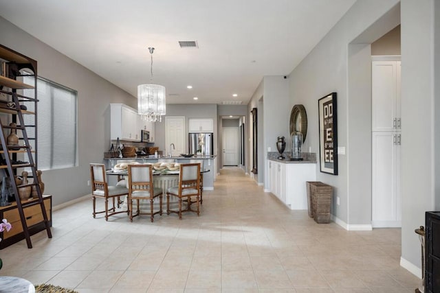 dining area with a notable chandelier, light tile patterned flooring, and sink