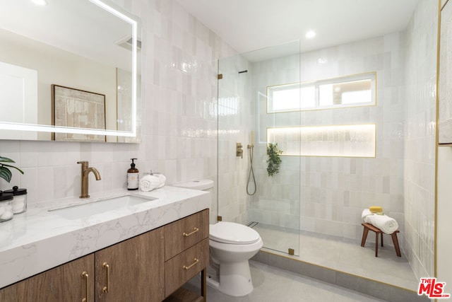 bathroom with toilet, vanity, tile walls, backsplash, and tiled shower