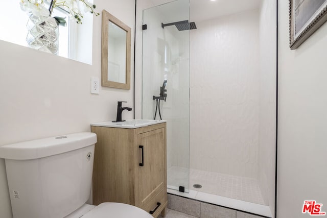 bathroom featuring toilet, vanity, and tiled shower