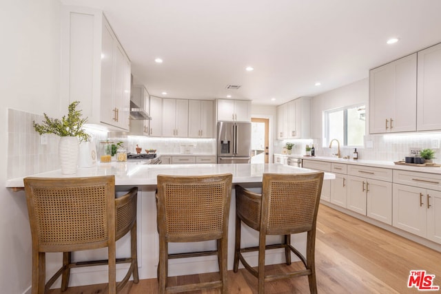 kitchen with a kitchen bar, white cabinets, and high end refrigerator