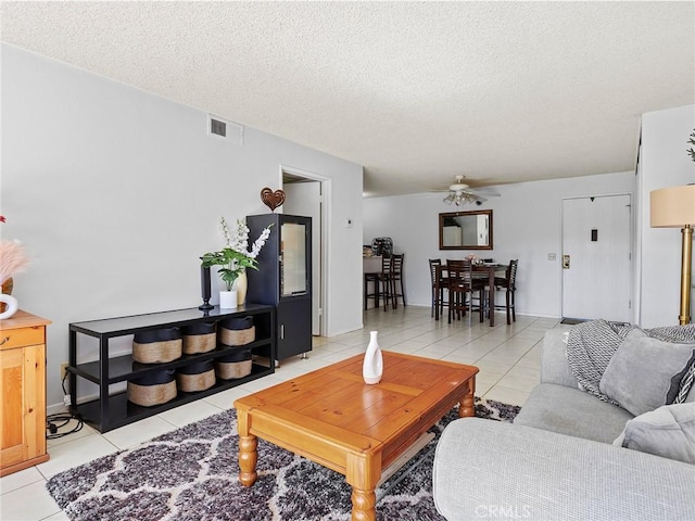 tiled living room with a textured ceiling and ceiling fan