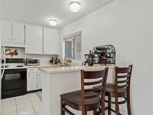 kitchen with kitchen peninsula, electric range, a kitchen breakfast bar, and white cabinetry