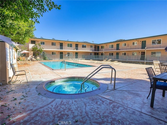 view of swimming pool featuring a community hot tub and a patio