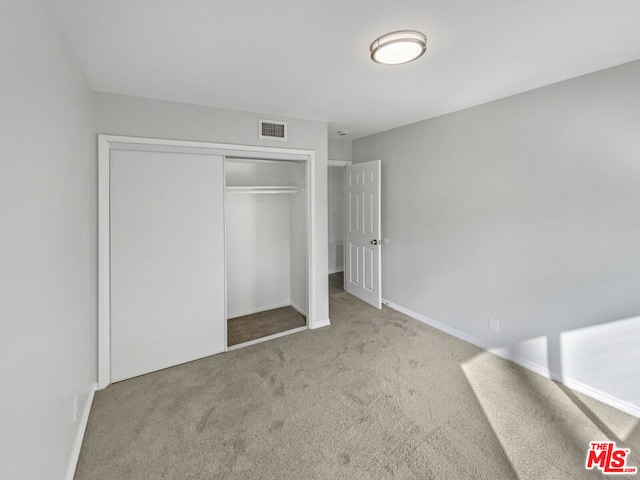 unfurnished bedroom featuring light carpet and a closet