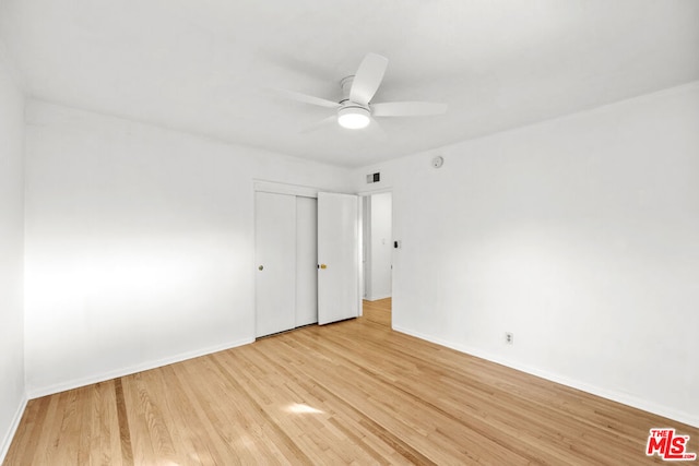 unfurnished bedroom featuring ceiling fan, a closet, and light wood-type flooring